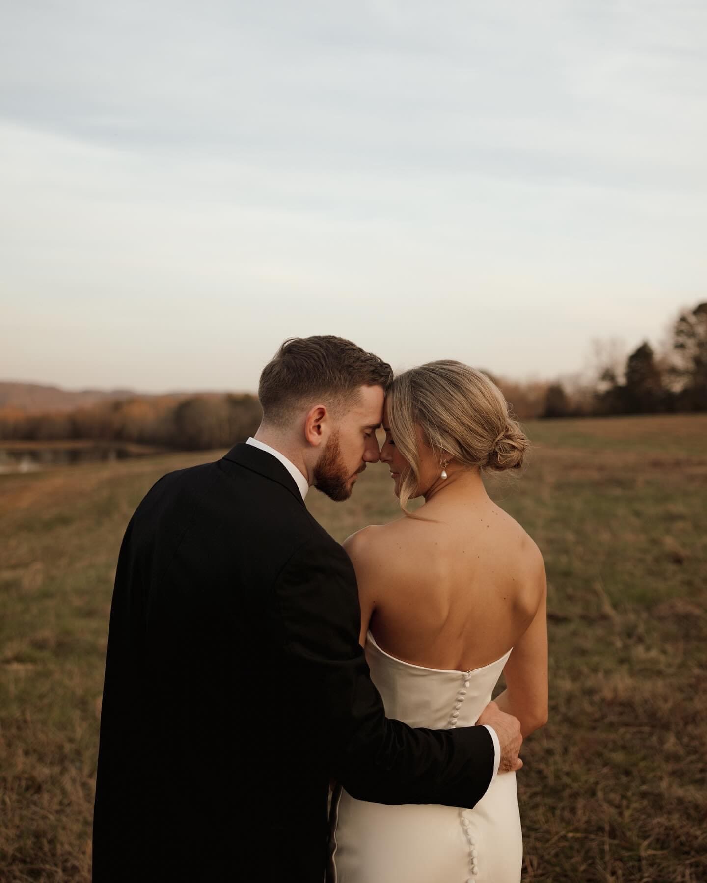 Bride and groom sharing an intimate moment in an open East Tennessee field at sunset, with soft golden light and elegant modern wedding attire.